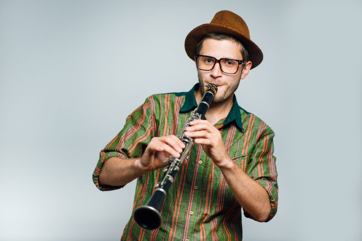 man playing clarinet wearing brown hat