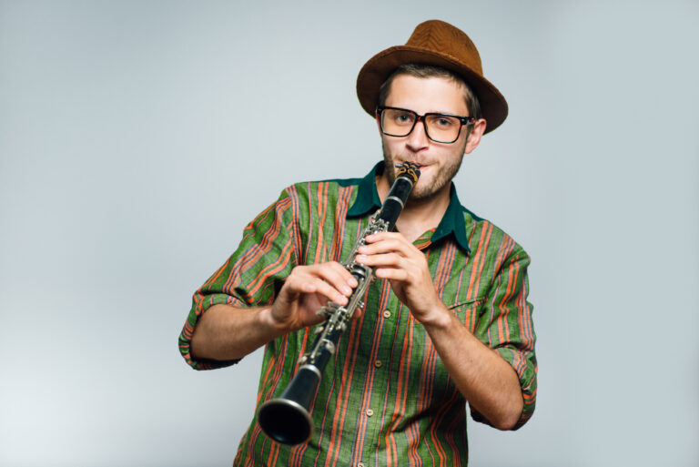 man playing clarinet wearing brown hat